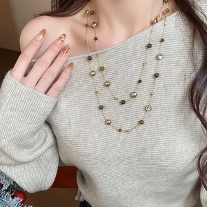 Detailed view of an elegant retro double-layered beaded necklace on a grey sweater model