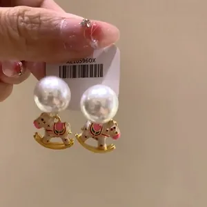 Detailed view of white rocking horse earrings with large pearls and gold accents