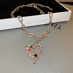 Detailaufnahme einer silbernen Herz-Halskette mit roten und schwarzen Zirkonia-Akzenten