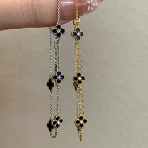 Close-up detail of gold and silver plated four-leaf clover bracelets with black stones
