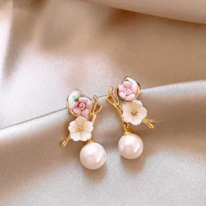 Close-up detail of elegant gold butterfly flower earrings with white pearl drops