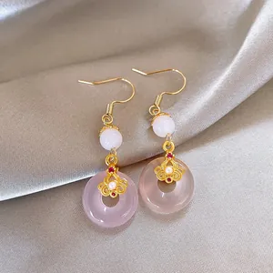 Close-up detail of elegant drop earrings featuring pink chalcedony and gold flower accents