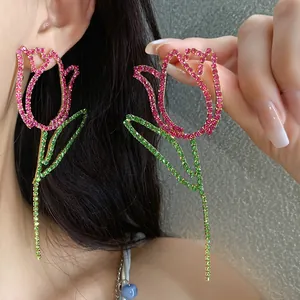 Detailed view of oversized tulip-shaped dangling earrings with pink and green rhinestones