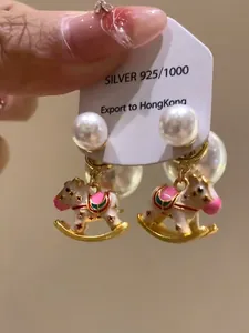Close-up of rocking horse pearl earrings featuring colorful enamel work and silver posts