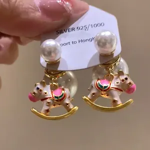 Detailed view of elegant enamel rocking horse earrings featuring white pearl studs