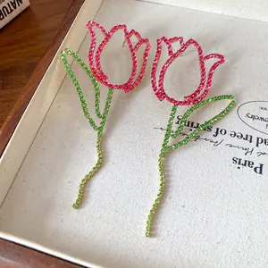 Close-up view of hollow tulip earrings decorated with vibrant pink and green rhinestones