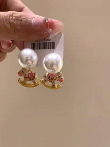 Detailed close-up of sweet rocking horse charm earrings with elegant large pearls
