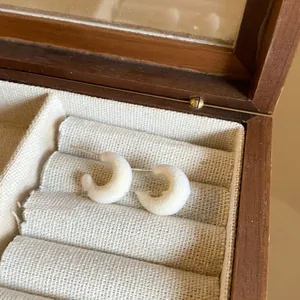Close-up detail of elegant white flocked C-shaped stud earrings with silver needles.