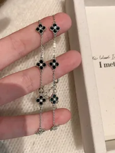 Close-up of silver-tone bracelets with black four-leaf clover charms and zircon stones