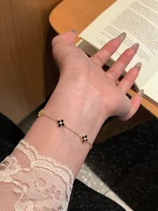 Detailed view of 18k gold plated clover bracelet with black charms on female wrist