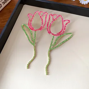 Close-up macro view of sparkling pink and green tulip earrings with long tassel stems