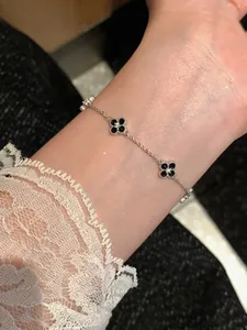 Detailed close-up of a silver bracelet with black zircon clover flower charms on wrist