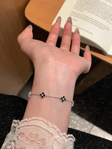 Detailed close-up of elegant silver clover flower bracelet with black motifs on a wrist
