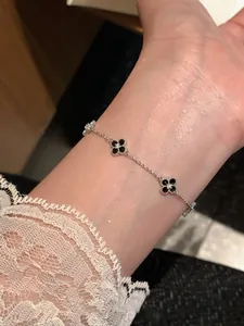 Close-up of elegant zircon flower bracelet with black clover charms worn on a wrist