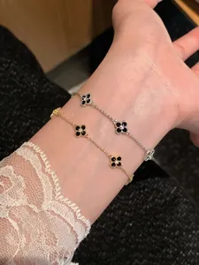 Detailed close-up view of gold and silver four-leaf clover bracelets worn on wrist