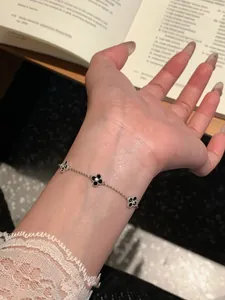 Detail view of silver-plated bracelet with zircon clover motifs worn on female wrist