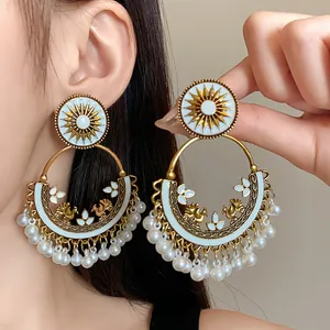 Detailed macro view of Bohemian ethnic hoop earrings with white enamel sun and pearl tassels