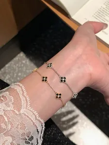 Close-up of elegant gold and silver clover charm bracelets with black zircons