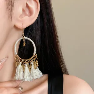 Detail shot of bohemian gold hoop earrings with white tassels on an Asian model