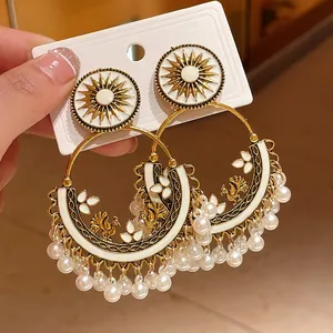 Detail view of Bohemian sun motif earrings featuring white enamel and pearl tassels