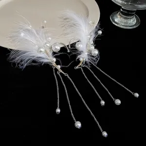 Elegantes orejeras etéreas con plumas blancas y borlas de perlas para orejas sin perforar.
