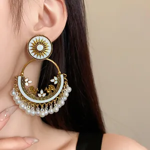 Close-up detail of ethnic Bohemian gold hoop earrings with white enamel and pearls