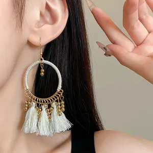 Detailed close-up showing white tassel hoop earrings with gold beads in bohemian style