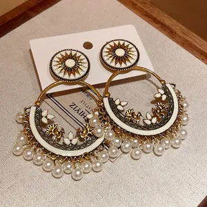 Detailed view of Bohemian ethnic earrings with sunburst motif, gold bird accents, and pearls.