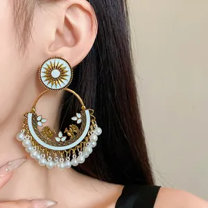 Detailed view of ethnic Bohemian dangle earring with sunburst motif and pearl tassels.