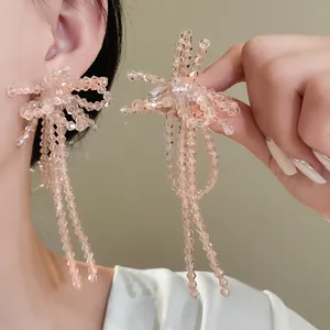 Primo piano di eleganti orecchini a fiocco con nappe in perle di vetro rosa su una modella