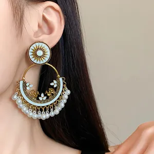 Elegant bohemian ethnic round gold earrings featuring white enamel birds and hanging pearls