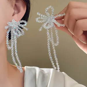 Dettaglio ravvicinato degli orecchini a fiocco in perle di vetro con lunghe nappe trasparenti