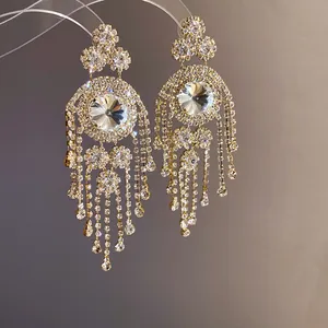 Makroaufnahme von luxuriösen goldfarbenen Kronleuchter-Ohrringen mit Strass-Fransen.