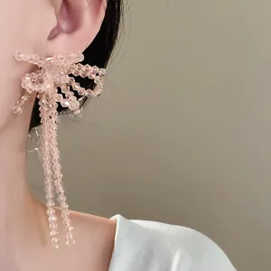 Vista dettagliata di orecchini a fiocco in perle di vetro rosa su una modella.