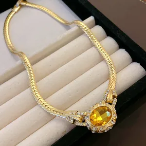Detailed macro shot of vintage gold snake chain necklace with yellow gemstone