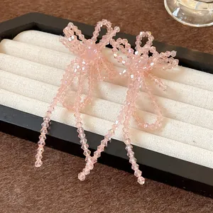 Primo piano di eleganti orecchini a fiocco in perle di vetro rosa con lunghe nappe