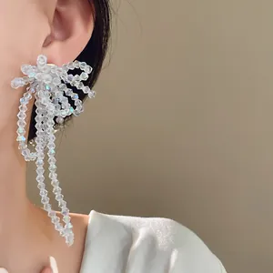 Primo piano di orecchini eleganti con fiocco e nappe con perle di vetro iridescenti