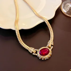 Close-up of vintage gold snake chain necklace with an ornate ruby-red gemstone pendant