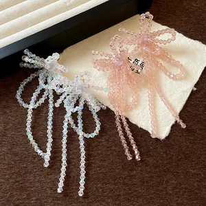 Dettaglio degli orecchini a fiocco fatti a mano con perle di vetro e nappe lunghe