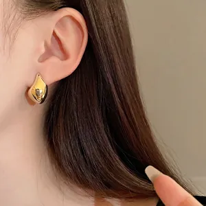 Elegantes pendientes de botón de metal dorado con forma de frijol para un look minimalista