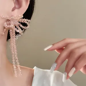 Dettaglio ravvicinato di orecchini a fiocco con perle di vetro rosa e nappe su modella