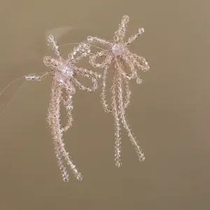 Dettaglio ravvicinato di orecchini a fiocco con nappe in perline di vetro rosa cipria
