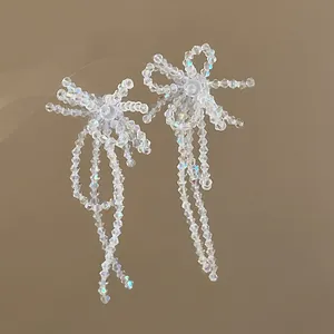 Dettaglio di orecchini a fiocco con nappe in perline di vetro iridescenti e argento
