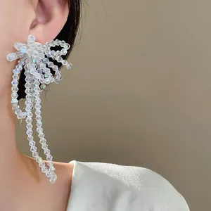 Dettaglio di eleganti orecchini a fiocco in perle di vetro con lunghe nappe al lobo
