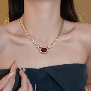 Detail view of a vintage gold-toned snake bone necklace with red rhinestone pendant