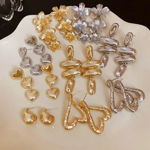 Colección de pendientes metálicos con forma de flores y corazones en bandeja cerámica