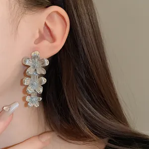 Vista detallada de los elegantes pendientes de tres flores de plata en el modelo