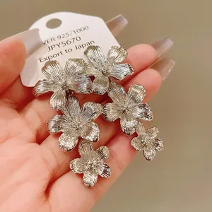 Primer plano de pendientes de flores plateadas con textura y etiqueta de plata 925