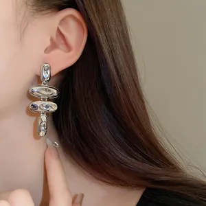 Primer plano de elegantes pendientes colgantes irregulares de metal plateado en una modelo
