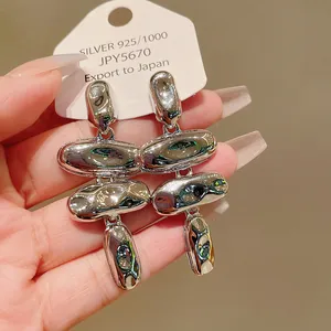 Primer plano de pendientes de metal líquido plateado con un diseño orgánico fluido.